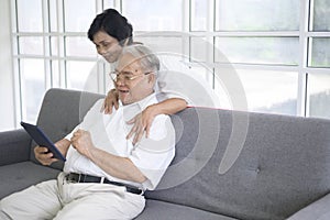 Happy senior Asian couple is using tablet and talking with family on webcam at home, retirement concept