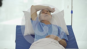 Happy senior Asian patient lying in hospital bed medical health insurance concept