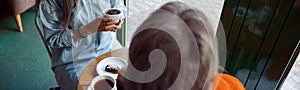 Happy senior Asian woman with friend look through window sitting at table in cafe