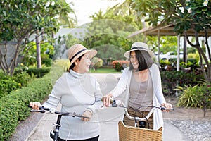 Happy senior asian women cycling bicycle with daughter at public park,Health insurance and elder care concept