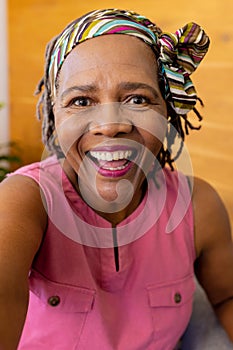 Happy senior biracial woman in headscarf making video call, smiling at home