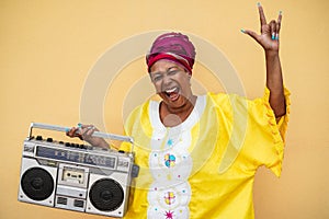 Happy senior black woman with traditional african dress dancing holding boombox stereo - Focus on face