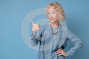 Happy senior blonde woman with thumbs up approving your choice.