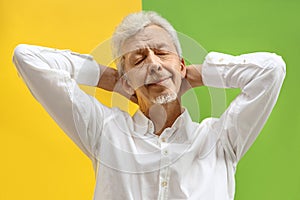 The happy senior business man standing and smiling against color background.