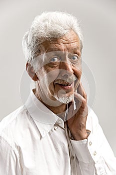 The happy senior business man standing and smiling against gray background.