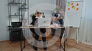 Happy senior business woman dancing victory dance celebrating weekend holiday success win in office