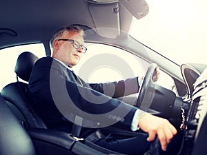 Happy senior businessman driving car