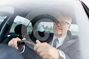 Happy senior businessman driving car