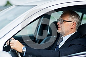 Happy senior businessman driving car