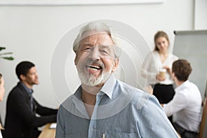 Happy senior businessman laughing looking at camera in office, p