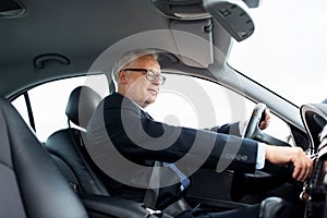 Happy senior businessman starting car and driving