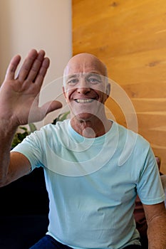 Happy senior caucasian man making video call smiling and waving at home