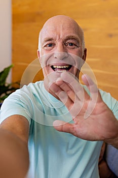 Happy senior caucasian man making video call smiling and waving at home
