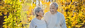 Happy senior citizens in the autumn forest. family, age, season and people concept - happy senior couple walking over