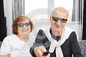 Happy senior couple with 3D glasses having fun on TV