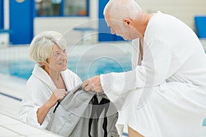 Happy senior couple in bathrobe by resort pool