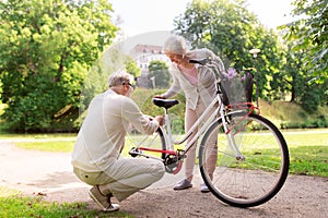 Happy senior couple with bicycle at summer park