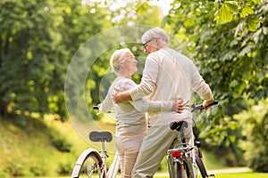 Happy senior couple with bicycles at summer park