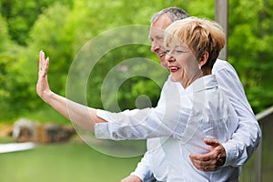 Happy senior couple on bridge waving hands