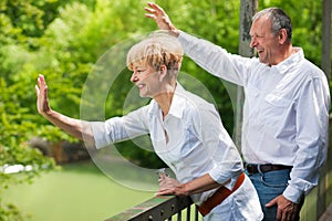 Happy senior couple on bridge waving hands photo