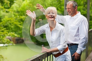 Happy senior couple on bridge waving hands