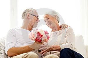 Happy senior couple with bunch of flowers at home