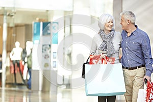 Happy Senior Couple Carrying Bags In Shopping Mall