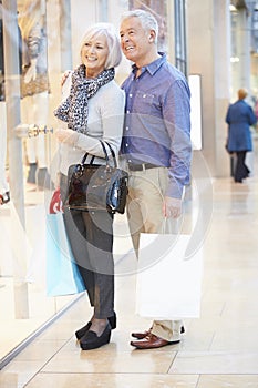 Happy Senior Couple Carrying Bags In Shopping Mall