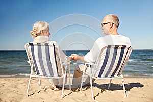 Happy senior couple in chairs on summer beach
