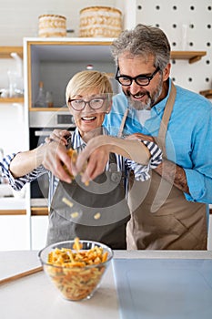 Happy senior couple cooking together and having fun in home kitchen