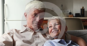 Happy senior couple cuddle on sofa enjoy love domestic comfort