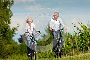 Happy senior couple cycling outdoors in summer