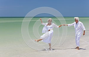 Happy Senior Couple Dancing Holding Hands on A Tropical Beach