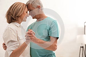 Happy senior couple dancing at home