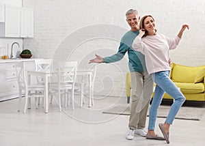 Happy senior couple dancing in kitchen