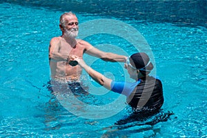 Happy Senior couple dancing In Swimming Pool Together. having fun .Swimming teacher . Holding hands, training , retirement,