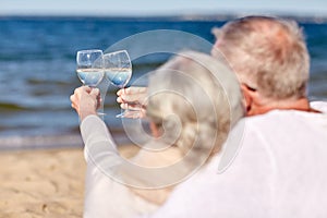 Happy senior couple drinking wine on summer beach