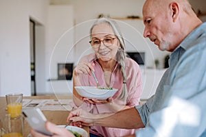 Happy senior couple eating dinner together at home.