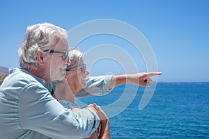 Happy senior couple embraced standing at the sea enjoying summer and sun