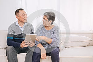 Happy senior couple enjoys technology together at home sofa. Tablet for elderly couples Strengthen family bonds with modern