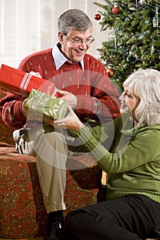 Happy senior couple exchanging Christmas gifts