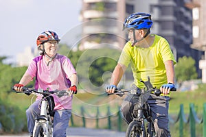 Happy  senior couple exercising with bicycles in the city park
