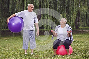 Happy senior couple with fitness balls in park