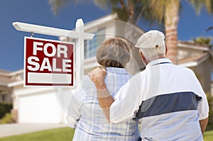 Happy Senior Couple Front of For Sale Sign and House