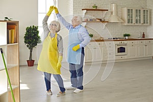 Happy senior couple having fun and dancing while tidying up their new apartment