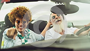 Happy senior couple having fun driving on new convertible car - Mature people enjoying time together during road trip