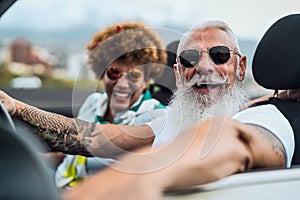 Happy senior couple having fun driving on new convertible car - Mature people enjoying time together during road trip