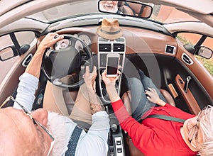 Happy senior couple having fun on new convertible car - Mature people enjoying time together during road trip vacation