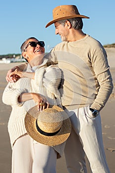 Happy senior couple having fun at seashore hugging and smiling