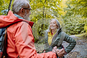 Happy senior couple hiking in autumn forest.